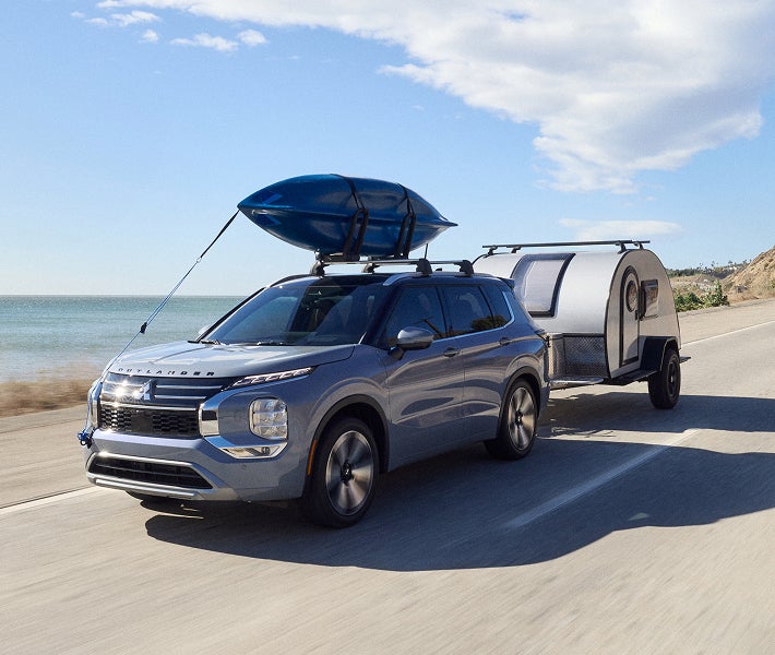 2026 Mitsubishi Outlander SUV towing a trailer to show off the vehicle's towing capacity.