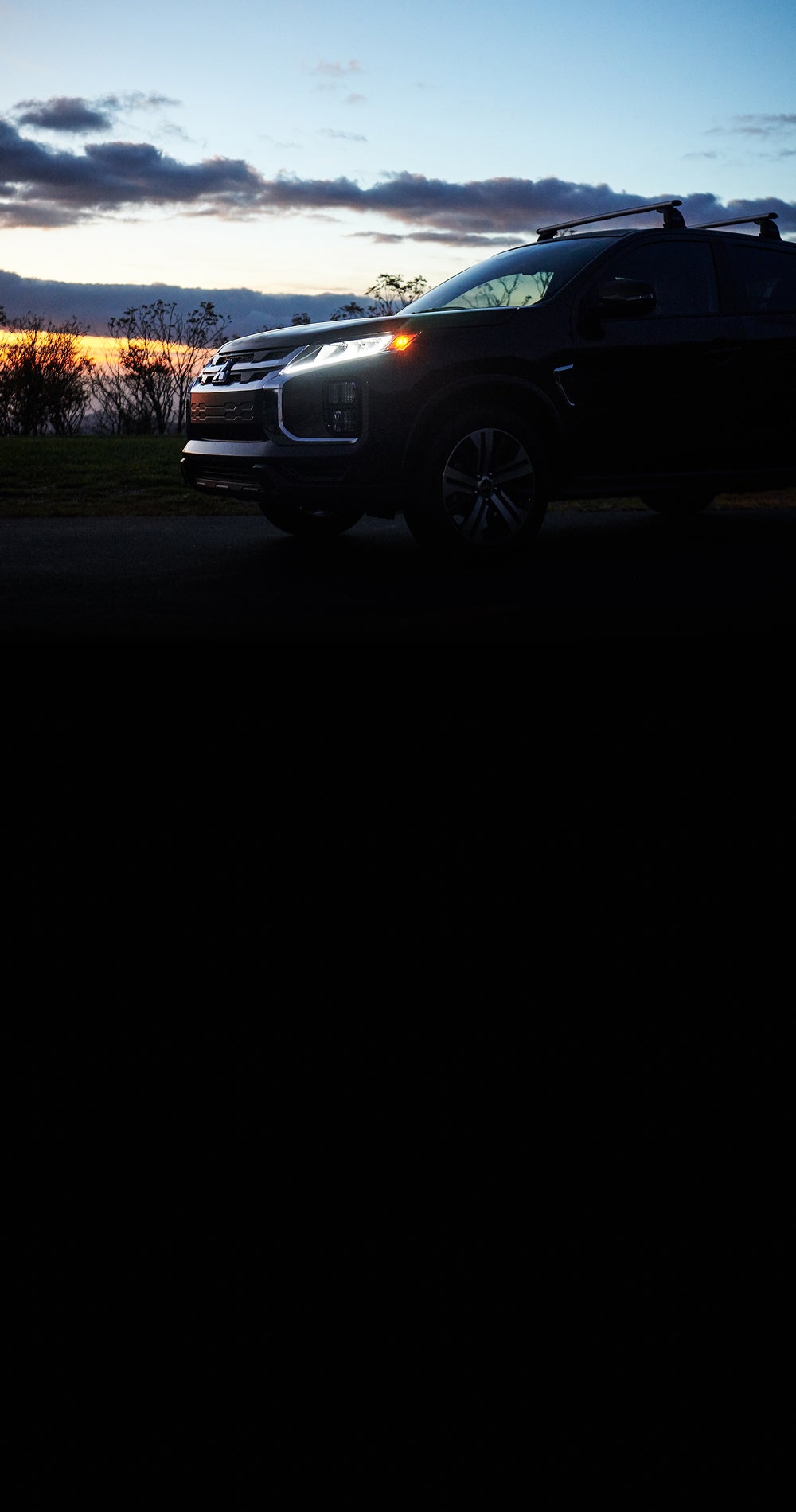 Dark lit side view of 2026 Mitsubishi Outlander Sport SUV with roof rack