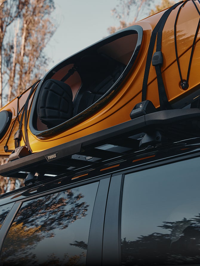 Close up on a kayak rack holding an orange kayak installed on the 2026 Mitsubishi Outlander SUV Trail Edition