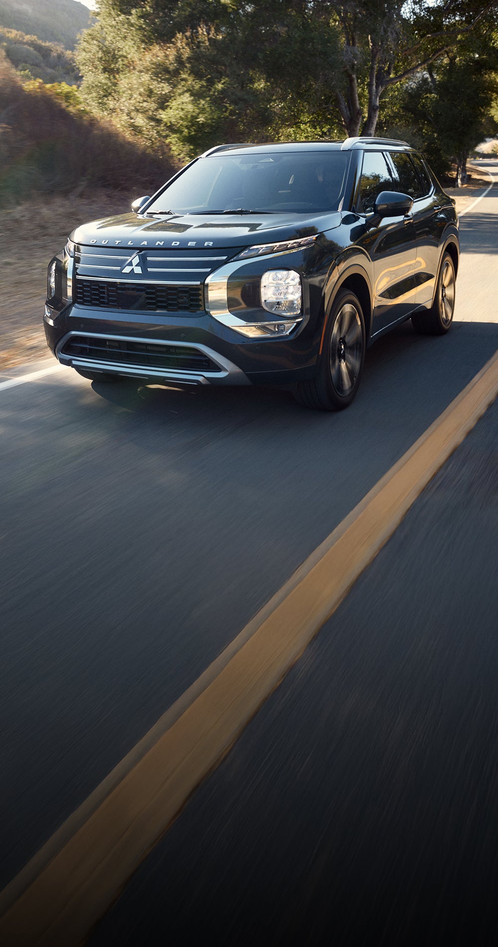 A black 2025 Mitsubishi Outlander SUV driving fast